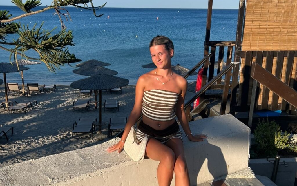 A hotel worker in Rhodes clears towels off reserved sunbeds