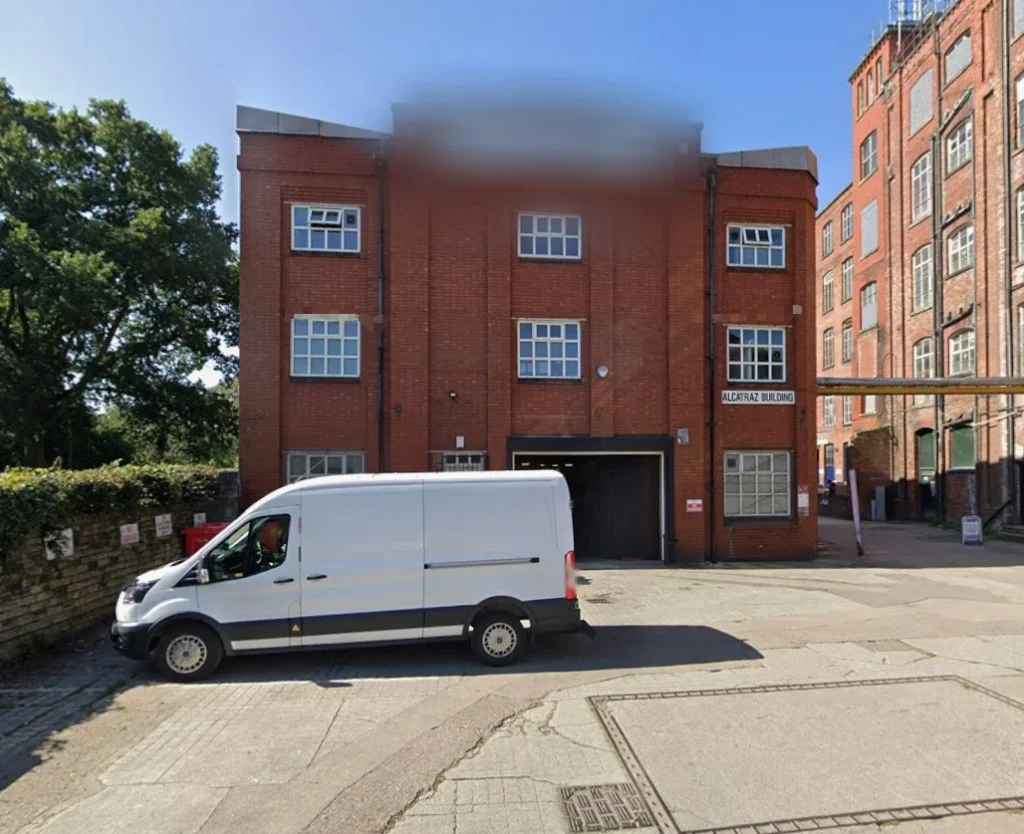 Stockport Pallet Warehouse brick building exterior with white van parked outside.
