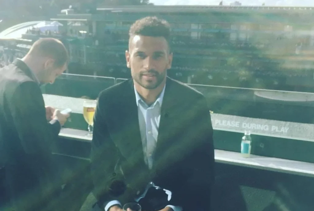 Steven Caulker in formal shirt crouching outdoors holding a camera