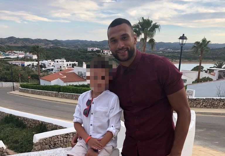 Steven Caulker holding a young child on a waterside balcony