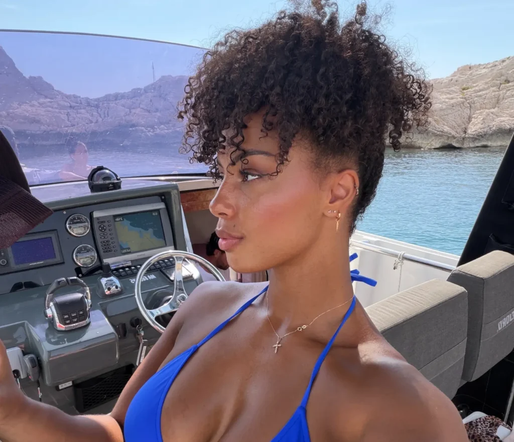 Woman at steering wheel of boat in blue bikini