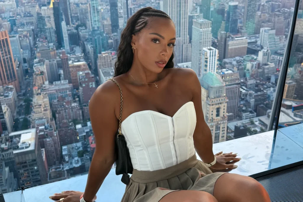 Woman in white corset top on high observation deck with city skyline behind