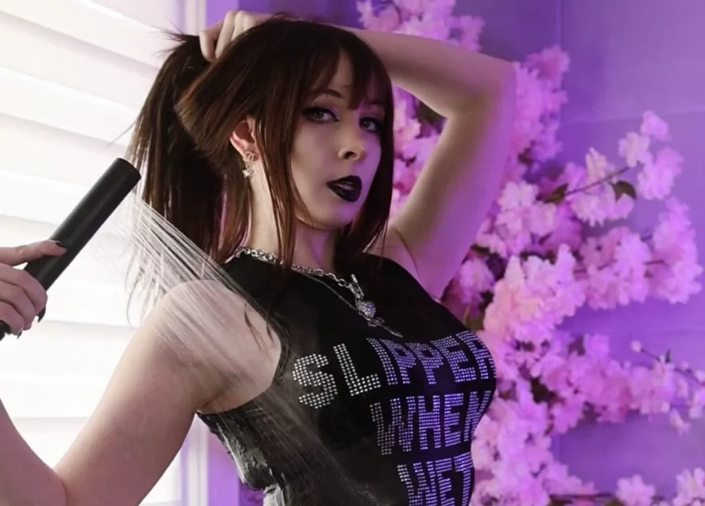 Woman in black top and shorts against purple floral background indoors.