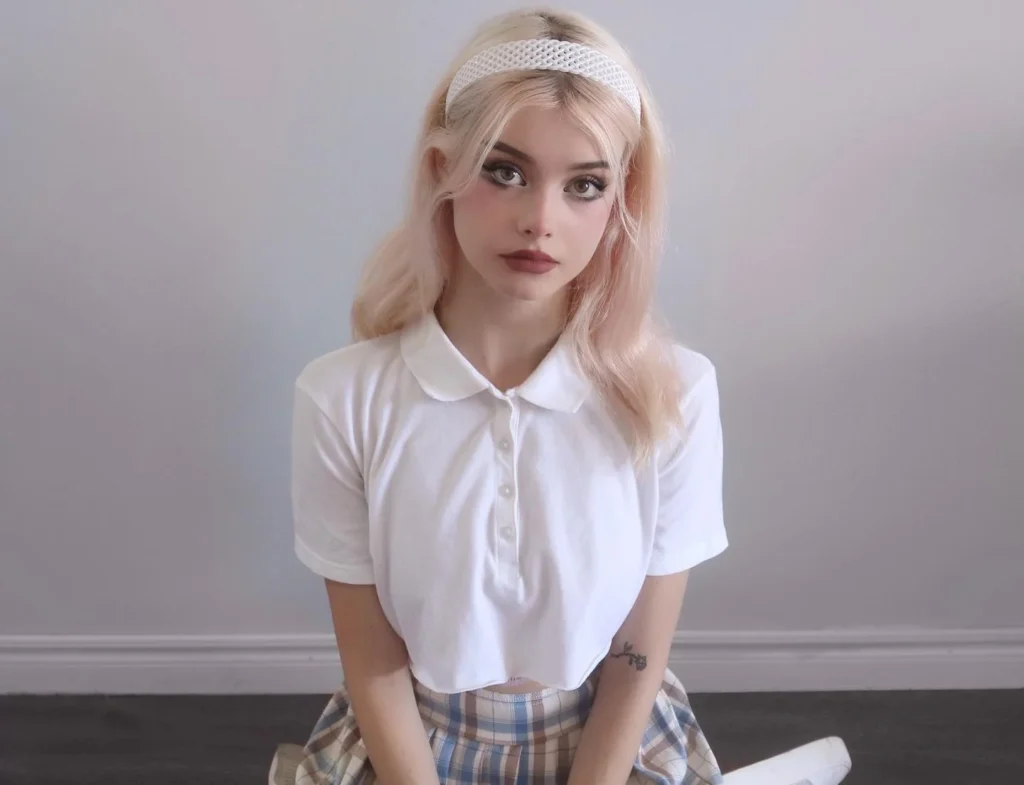 Lauren Burch in white shirt and plaid skirt with blonde hair