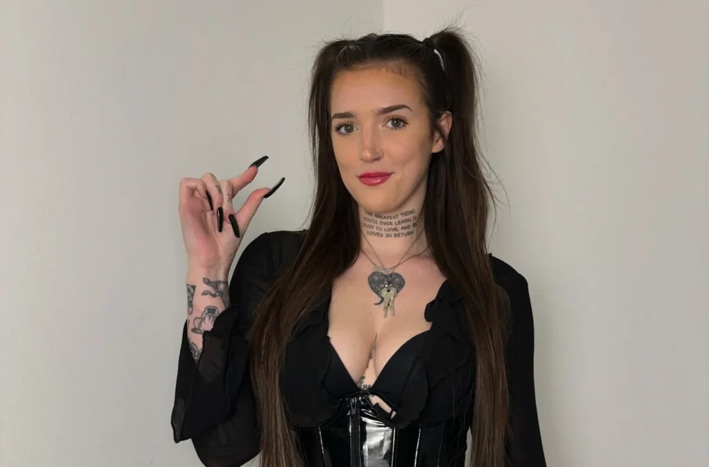 Woman in black latex coat dress holding cigarette prop.