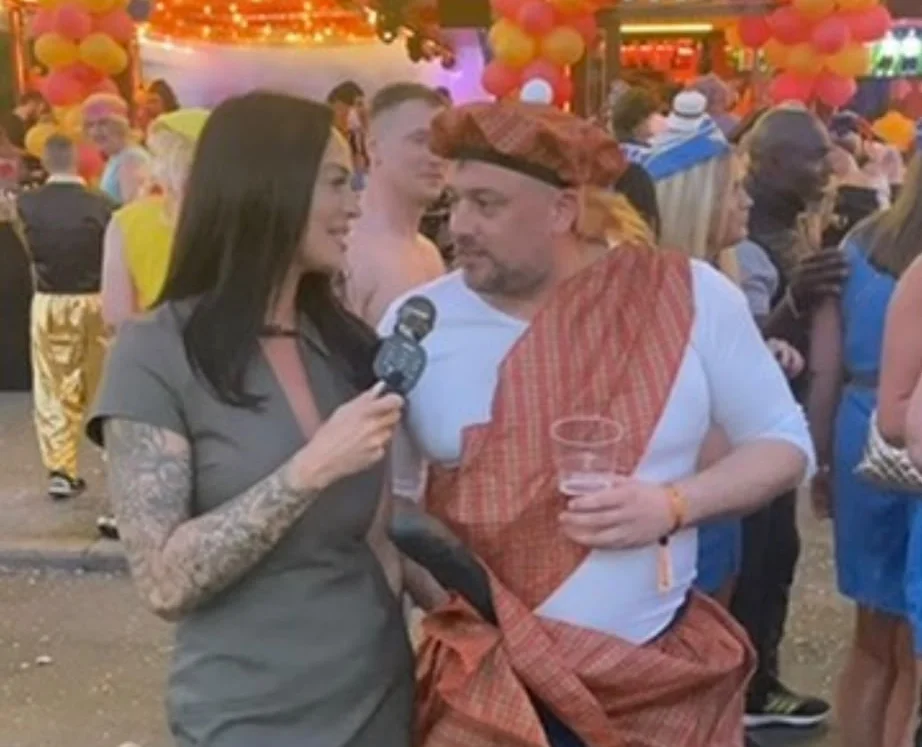 Woman interviewing man at outdoor public event with microphone.