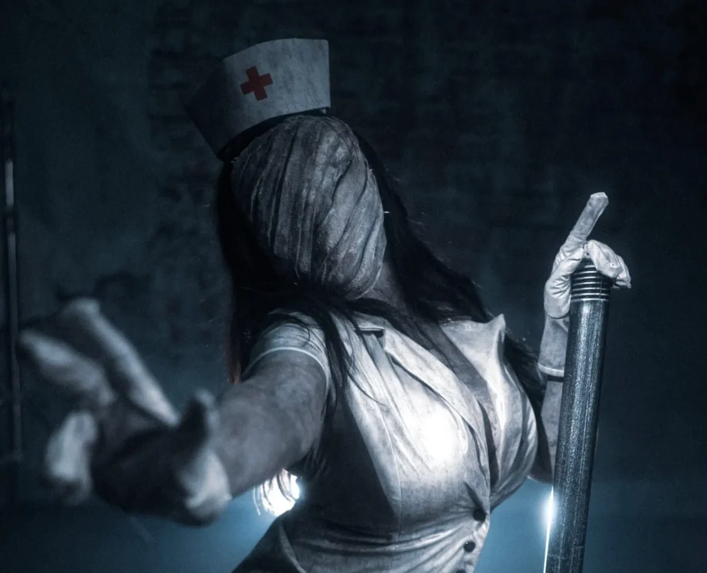 Woman in dark nurse costume with face obscured by mask standing indoors.