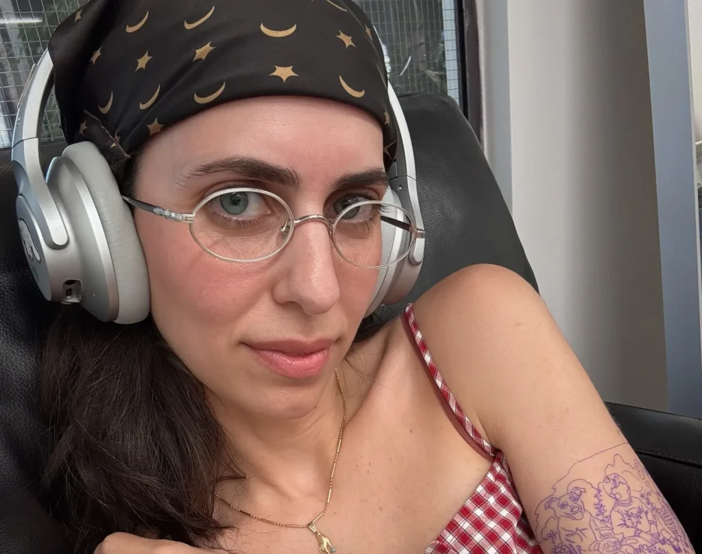 Hila Klein in outdoor hot tub wearing swimwear, reclining in water