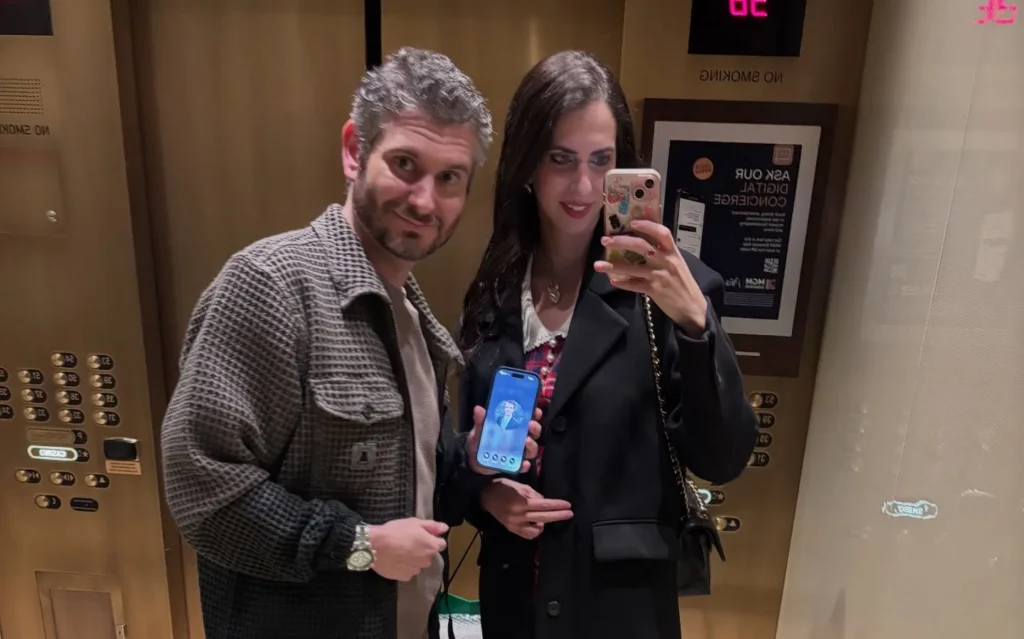 Ethan and Hila Klein standing together in a lift, taking a mirror selfie