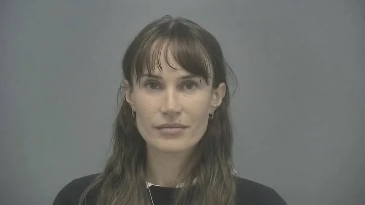 Mugshot of woman with dark hair and fringe.