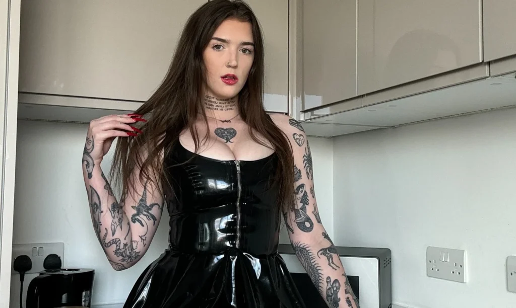 Woman in black latex dress in minimalist white room.