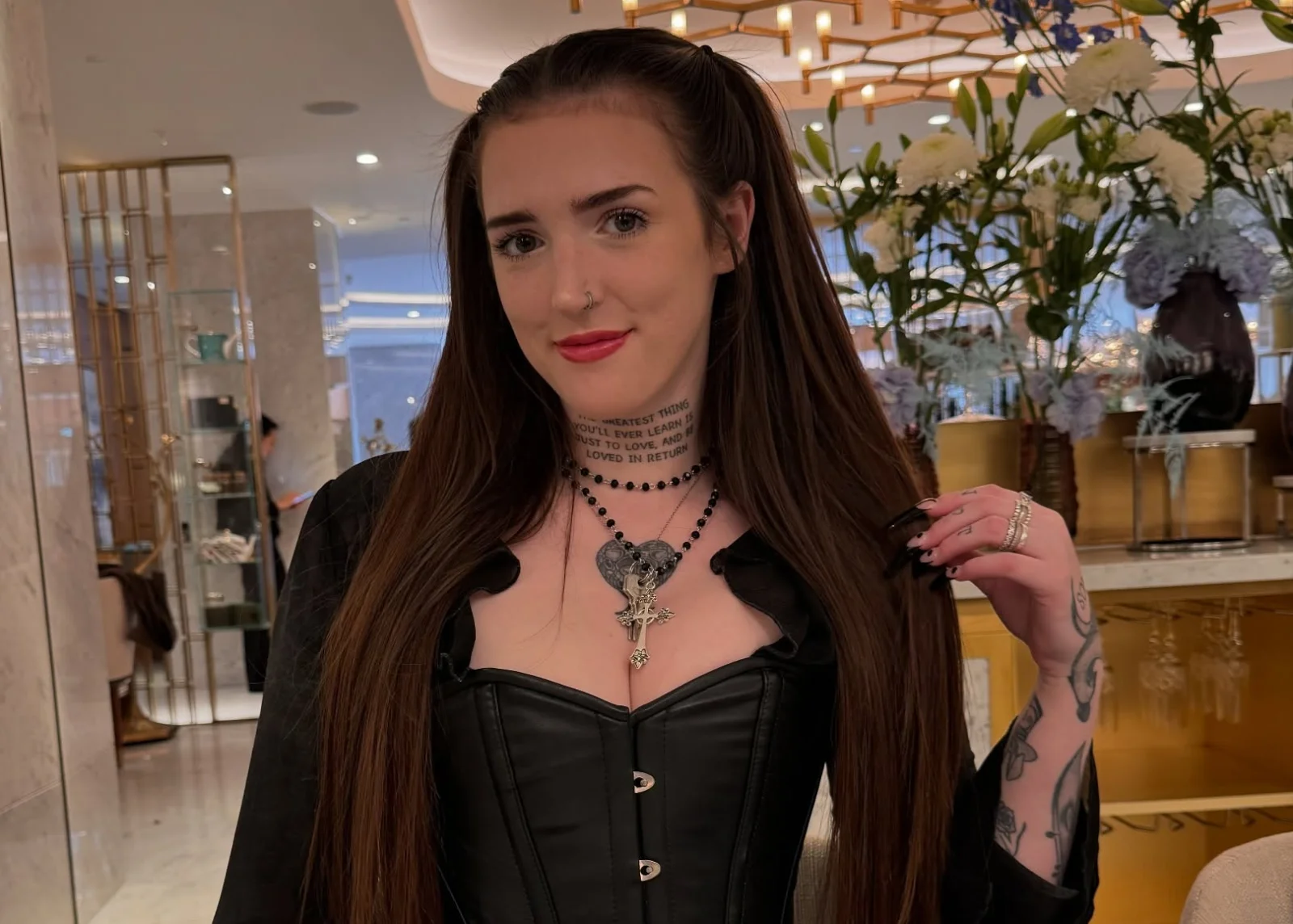Woman with long dark hair in black corseted outfit at restaurant.
