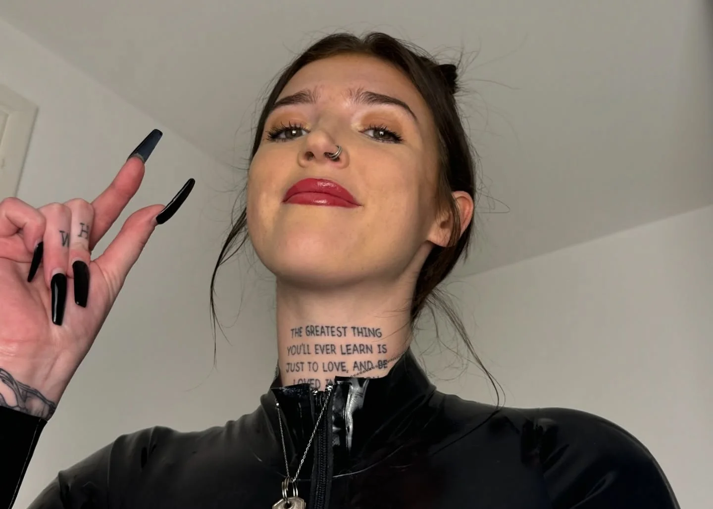 Woman with dark hair wearing black latex dress holding cigarette lighter.
